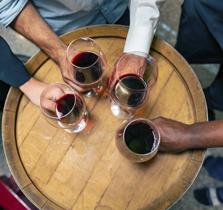 manos sujetando copas de vino sobre barril